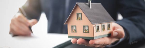 Real estate agent is holding a house model. Buy, loan for a house